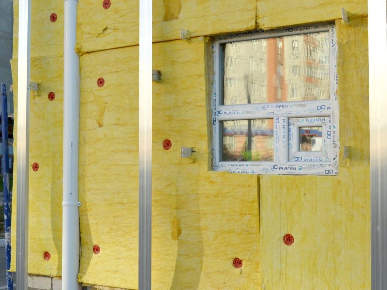 BEG Einzelmaßnahme Außenwand Gelbe Dämmplatten an einer Wand mit einem kleineren Fenster in der Mitte. Beispiel einer BEG-EM Einzelmaßnahme an der Gebäudehülle.